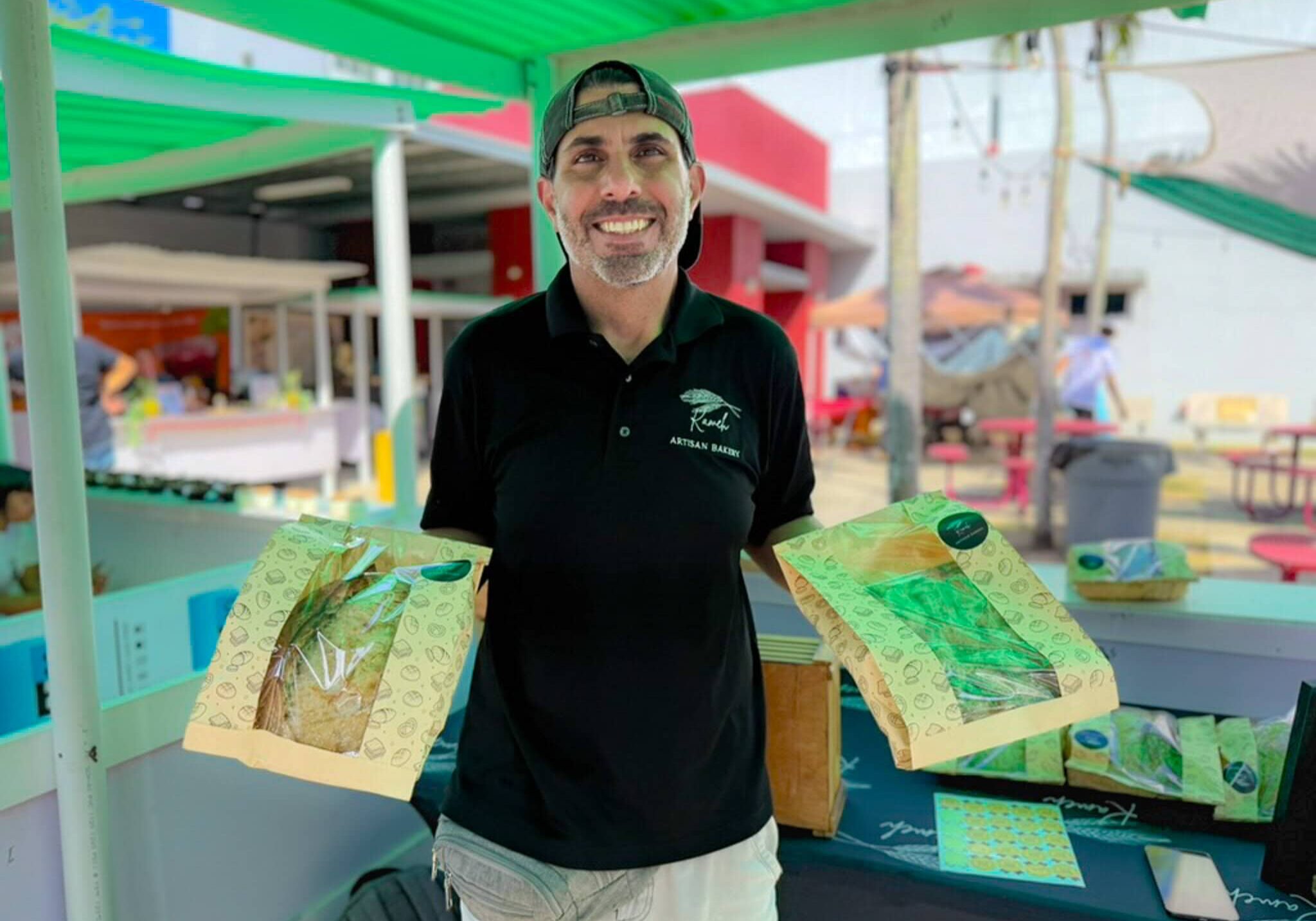 Nizar, founder of Kameh Artisan Bakery, holding artisan sourdough bread at a Puerto Rico farmers market. Featured in the Puerto Rico Local Spotlight series.